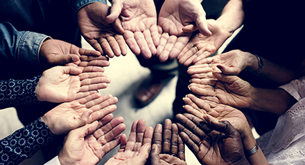 hands open palm up in a circle of different races of humans