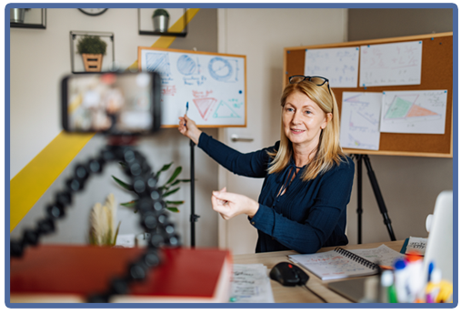 female instructor pointing to board while recording on cell phone