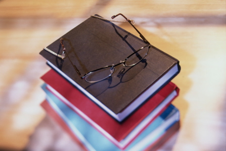 stack of hardback books with eyeglasses on top of th stack