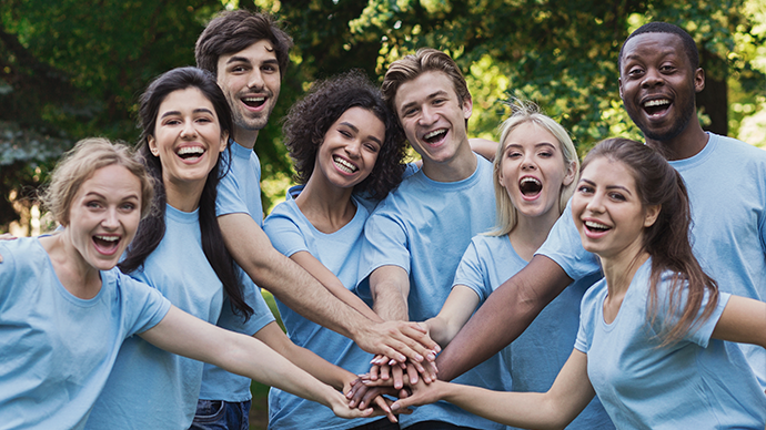 group of volunteers hands on top of each other smiling.