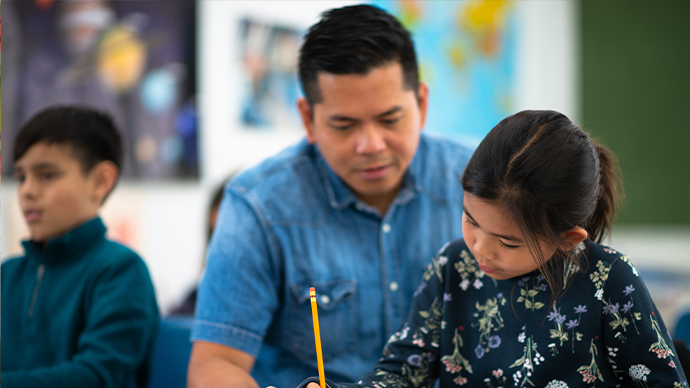 Teacher with student at her desk.