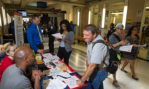 student stopping by a info table